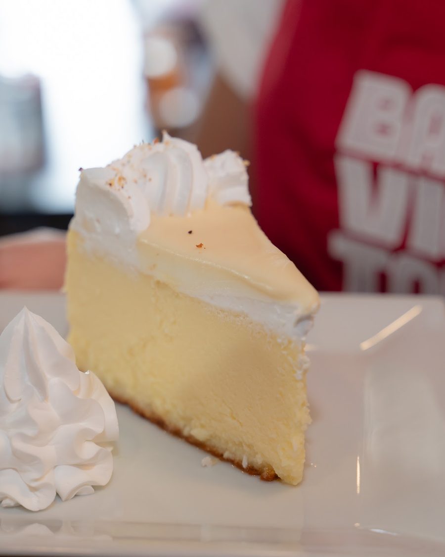 A slice of key lime cheesecake with a swirl of whipped cream