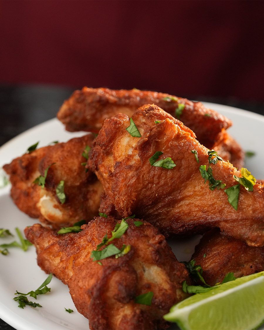 Mojo chicken wings with chopped cilantro and a lime wedge